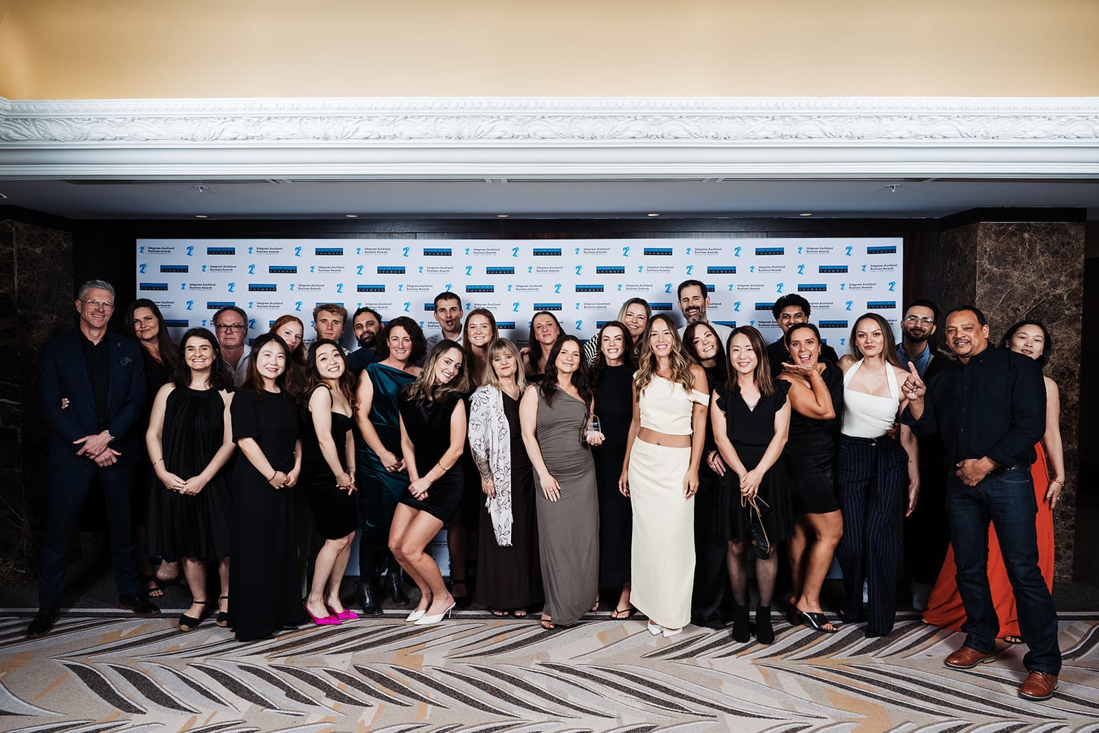 Henry Barfoot of Barfoot & Thompson on the far left with most of the Aspire Property Management team, photographed in front of the awards backdrop at the Cordis Hotel