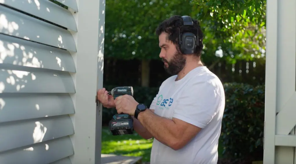 An Aspire maintenance technician using a cordless drill to repair a louvred exterior panel