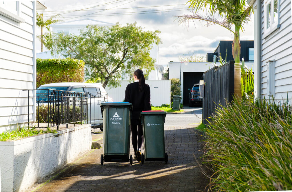 A lady taking out rubbish bins to the driveway